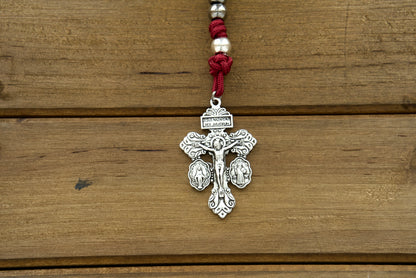 Durable maroon paracord rosary with gunmetal and silver beads, featuring St. Benedict medal centerpiece and standard 2" Pardon Crucifix, perfect for devout Catholics seeking spiritual protection and guidance.