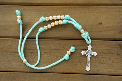 Embrace the beauty of faith with our Teal and Rose Gold Rearview Mirror Paracord Rosary. This stunning rosary, handcrafted by a devoted Catholic family, offers unbeatable durability and spiritual guidance on life's journey. Featuring 10mm rose gold beads and a St. Benedict Crucifix, it's the perfect accessory for any faithful woman. 