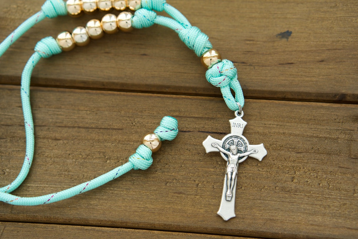Teal and Rose Gold - Rearview Mirror Paracord Rosary: A stunning, durable paracord rosary for Catholic women, featuring teal blue paracord with rainbow ribbon intertwined and rose gold 10mm beads. Perfect for constant inspiration and spiritual guidance on the go.