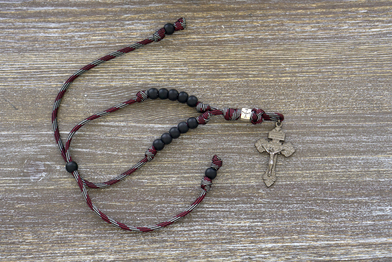 The Crusader Rearview Mirror Rosary - a durable paracord rosary designed for on-the-go prayers, featuring metal Crusader bead, acrylic beads, and a gunmetal pardon crucifix.