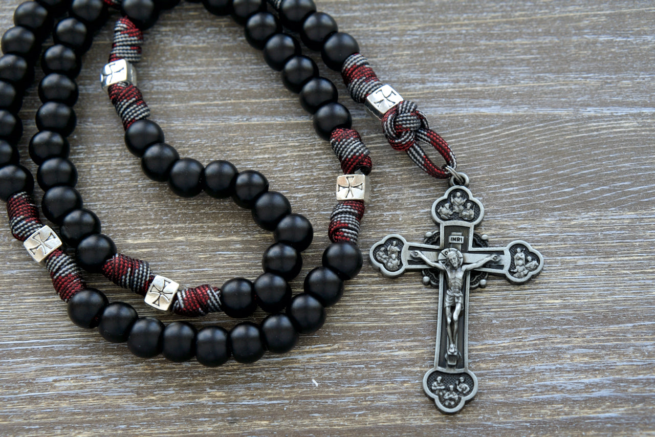 The Crusader - DEUS VULT! 5 Decade Unbreakable Paracord Rosary, featuring bold black, red, and gunmetal colors, large gunmetal Crucifix, full-size St. Benedict medal, and perfect for young Catholic warriors in their spiritual battles. Shop now at Sanctus Servo for this powerful Catholic gift!