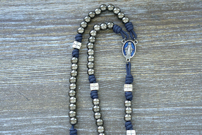 "The Solemn Crusader" Premium Metal Paracord Rosary featuring navy blue paracord, silver crusader Our Father beads, gunmetal Hail Mary beads, and a blue enamel Miraculous Medal centerpiece.