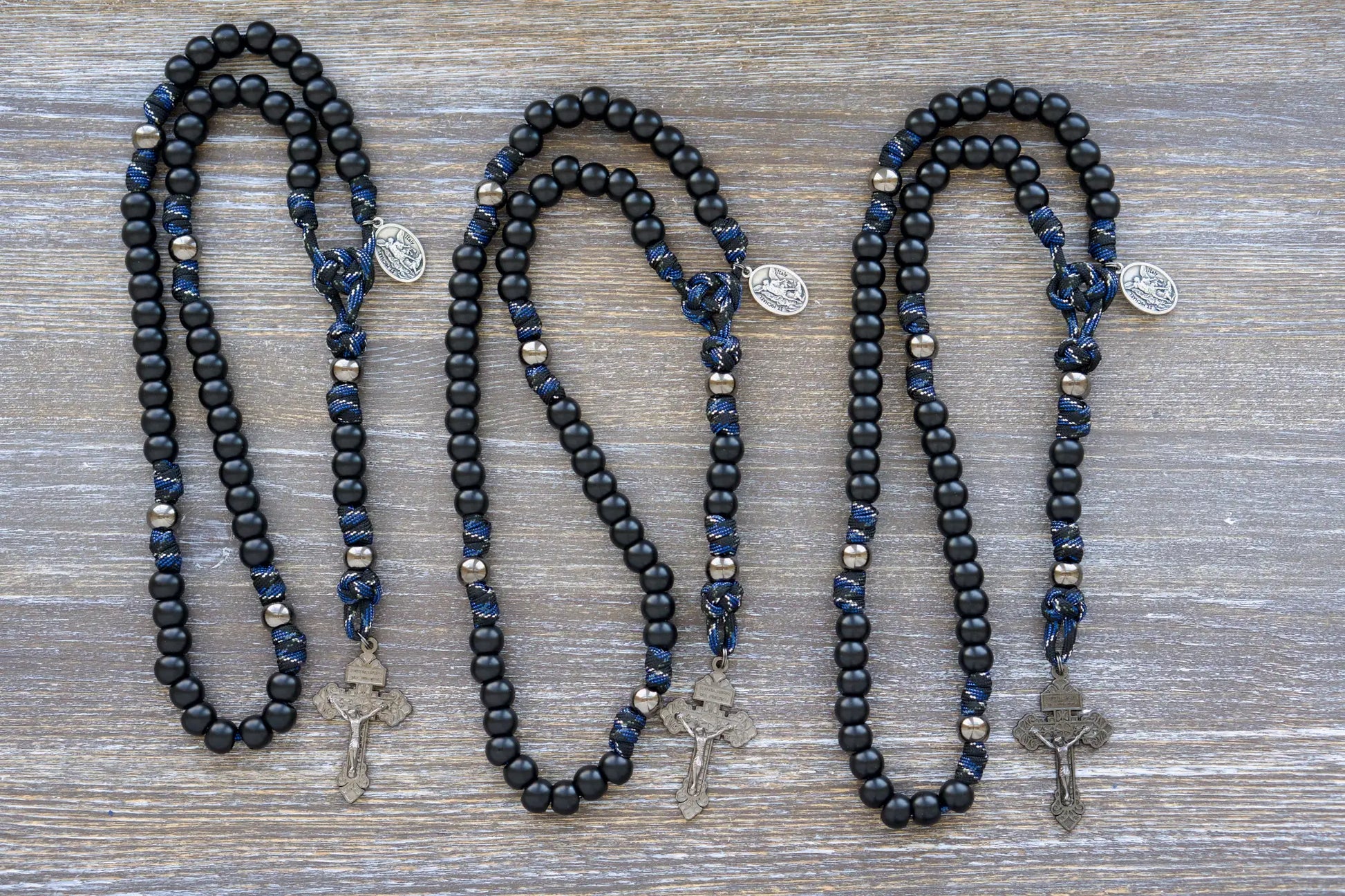 Thin Blue Line - 5 Decade Paracord Rosary: Camo paracord, matte black Hail Mary beads, gunmetal Our Father beads, and a devotional medal featuring St. Michael and a Guardian Angel. 
