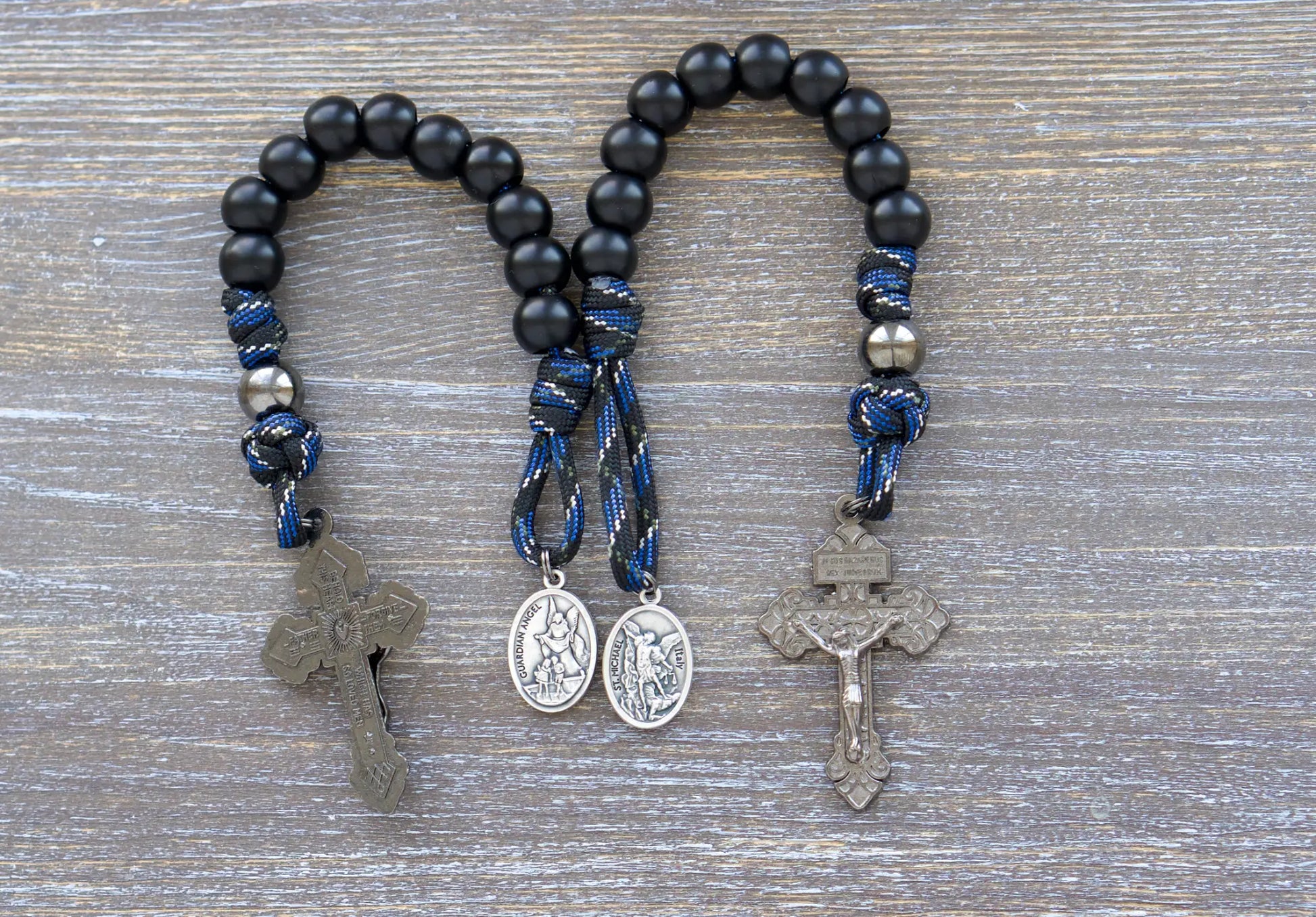 Thin Blue Line Pocket Rosary: Black/blue camo paracord with gunmetal and matte black acrylic beads, featuring a St. Michael medal and gunmetal crucifix.