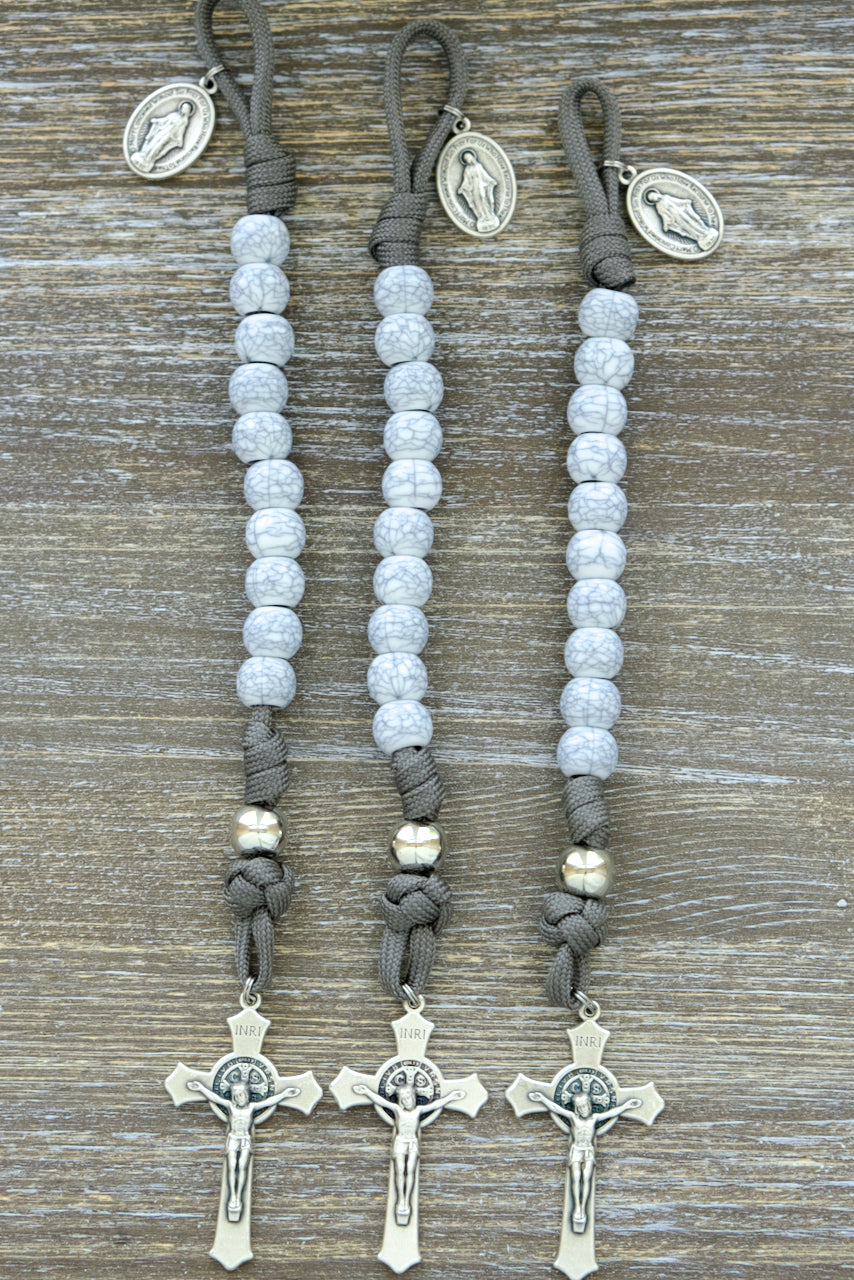 Tower of Ivory - Pocket Paracord Rosary: A stunning and durable 1 decade rosary featuring 12mm acrylic beads, dark grey paracord, silver Our Father beads, and cracked ivory-looking Hail Mary beads. Includes a 2-inch St. Benedict crucifix and Miraculous Medal for added spiritual protection.