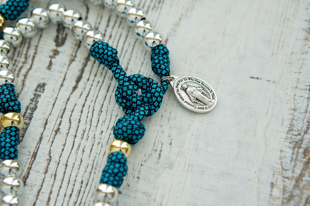 Embrace the unbreakable bond with this Turquoise and Silver 5 Decade Paracord Rosary - an indestructible weapon for your spiritual battles. Featuring a Miraculous Medal and premium materials, our handmade rosaries are perfect for Catholic devotees of all ages. 