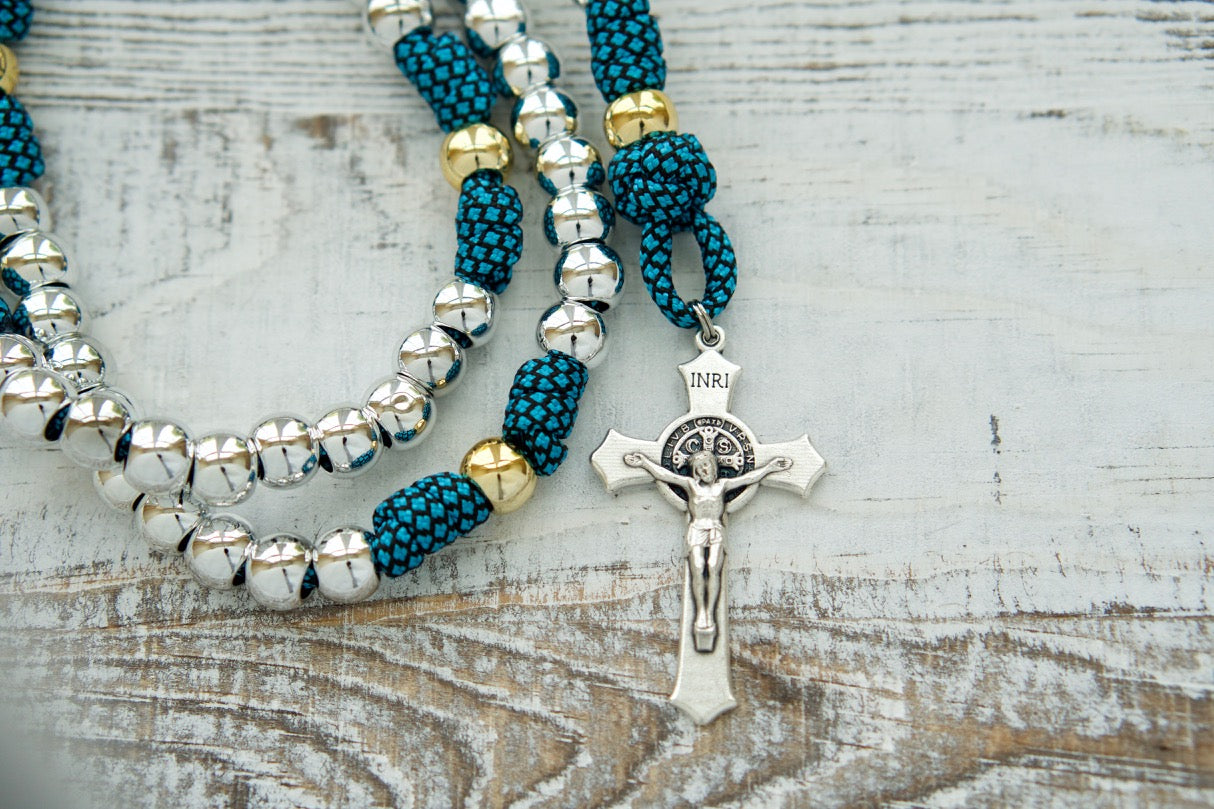 Embrace the Unbreakable Bond - Turquoise and Silver - 5 Decade Paracord Rosary, an indestructible Catholic gift designed to empower your spiritual journey. This premium paracord rosary features a stunning Turquoise and Silver design with smaller 10mm beads and a standard size 2" St. Benedict Crucifix for easy use during prayer sessions.