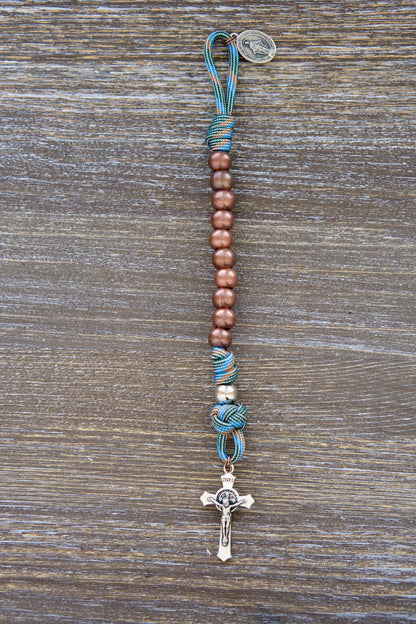 Bright light blue and copper paracord rosary with acrylic beads and Miraculous Medal, styled for young boys' Catholic adventures.