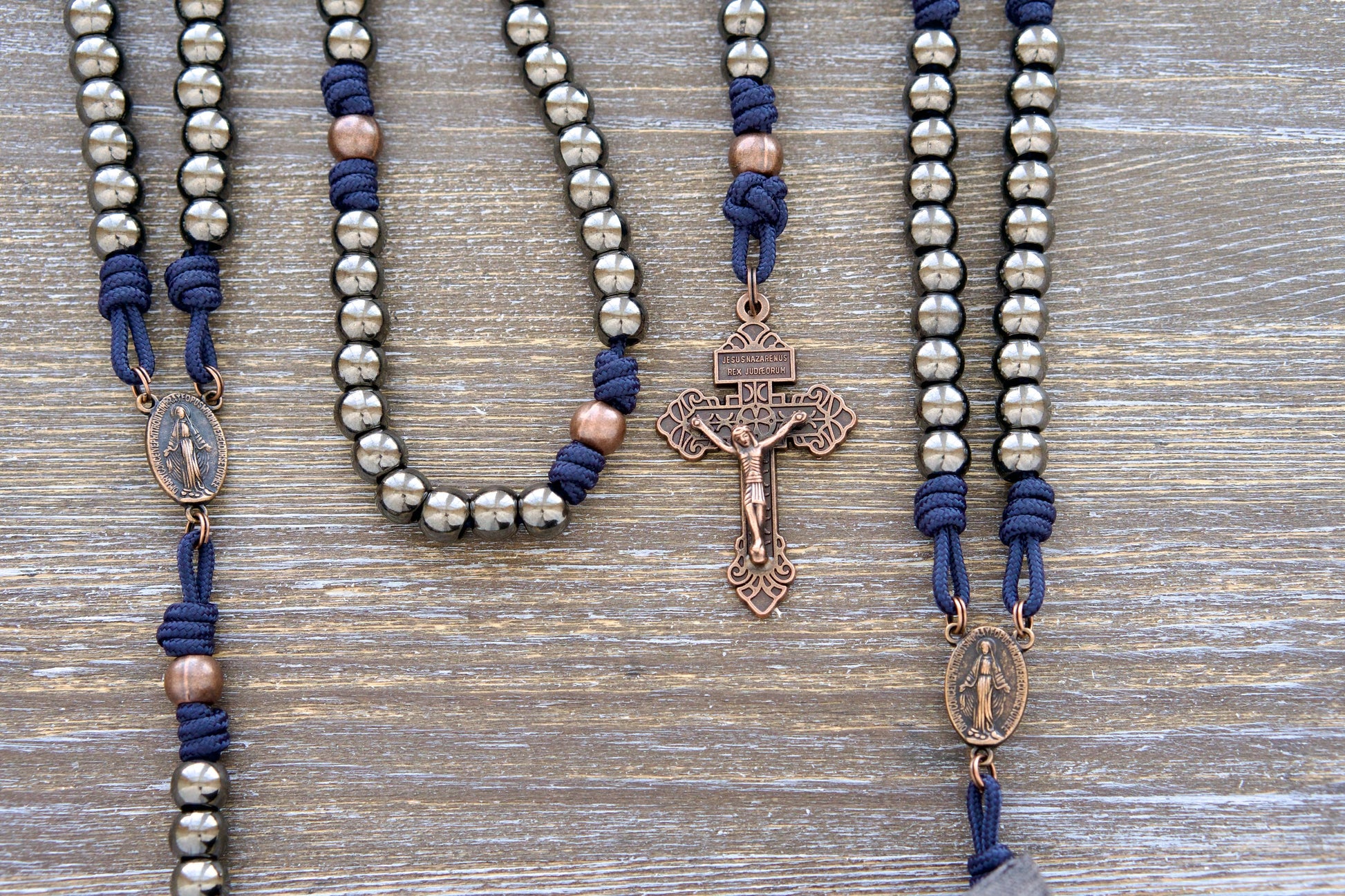 Unbreakable Fidelity Rosary: Navy blue paracord, 10mm gunmetal Hail Mary beads, antique copper Our Father beads, copper Miraculous Medal centerpiece, and copper Pardon Crucifix. Durable & stylish rosary perfect for everyday carry.