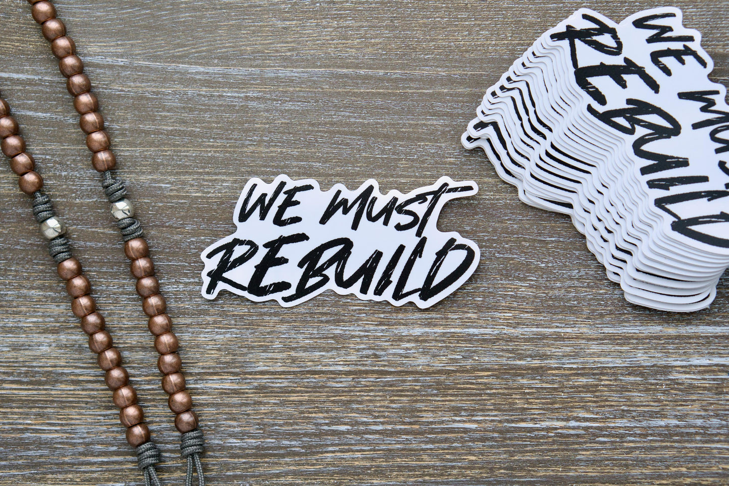 We Must Rebuild white vinyl sticker, 4.25" x 2.13", features a bold call to action for restoring faith, society, and families based on Isaiah 61:4.