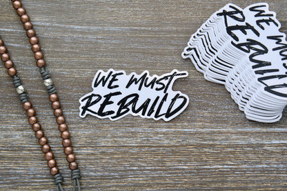 We Must Rebuild white vinyl sticker, 4.25" x 2.13", features a bold call to action for restoring faith, society, and families based on Isaiah 61:4.