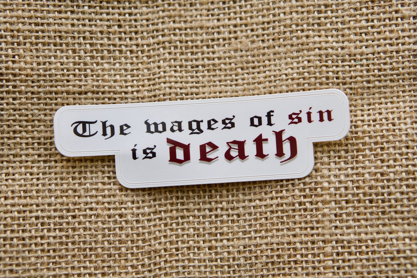 Wages of Sin - Vinyl Sticker: A powerful reminder of the consequences of sin, featuring Romans 6:23 on a durable 4" x 1" sticker. Perfect for laptops, water bottles, and more. Pair with a Sanctus Servo rosary for a thoughtful Catholic gift.