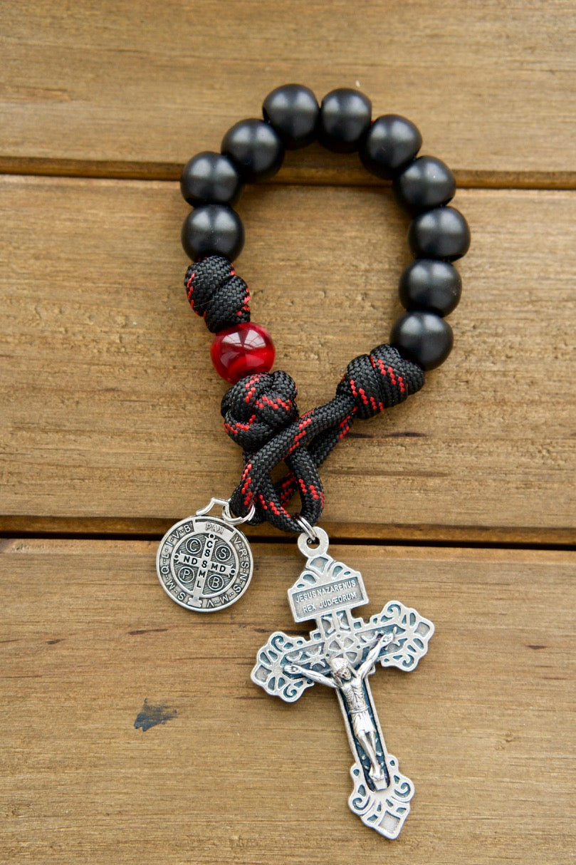 Embrace the sacrifice of Jesus with The Blood of Christ - 1 Decade Paracord Rosary. This durable, premium paracord rosary features a silver pardon crucifix, a St. Benedict medal, and striking black and red rope with black and maroon/red beads for a powerful symbol of faith and devotion.