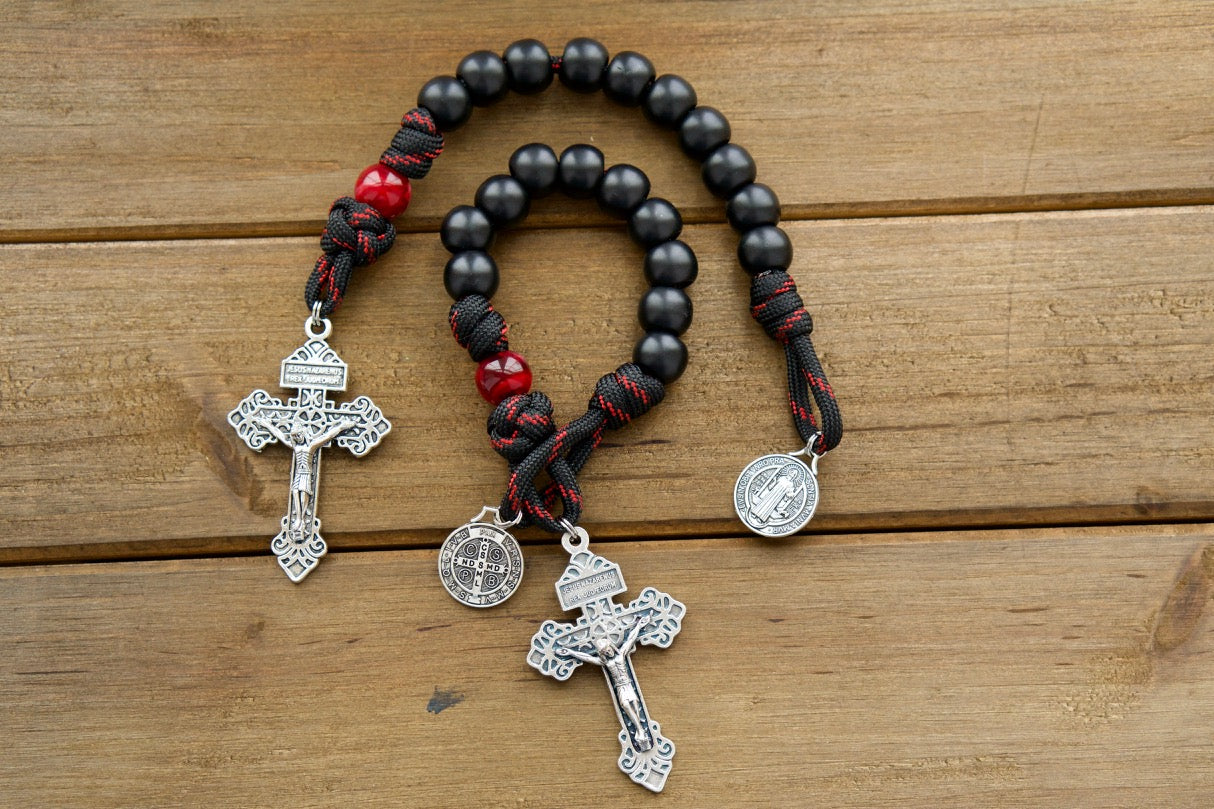 The Blood of Christ - 1 Decade Paracord Rosary, featuring a silver pardon crucifix and a St. Benedict medal in black and maroon/red rope with beads. A durable, premium, unbreakable paracord rosary for Catholic gifts that honors the sacrifice of Jesus on the cross. 