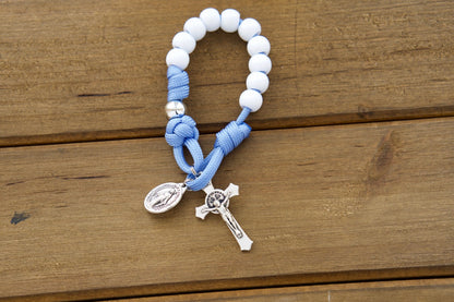 Children's Blue, White and Silver - 1 Decade Paracord Rosary A colorful image showcases a beautiful kid's light blue paracord pocket rosary. The rosary features white Hail Mary beads and silver Our Father beads, making it easy for children to follow along and stay focused on their prayers.