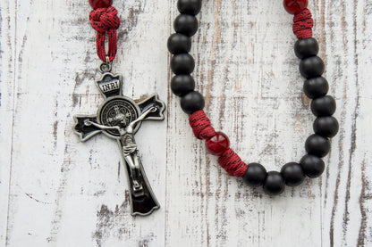 The "Crimson Shield Holy Spirit Confirmation - 5 Decade Paracord Rosary" stands as a testament to strength and resilience in faith. This premium paracord rosary is crafted with sturdy 550 paracord in deep maroon red, accompanied by dark maroon Our Father beads and matte black Hail Mary beads. The 3" St. Benedict crucifix, adorned with black enamel, adds a touch of protection to the rosary while emphasizing its power and importance. 