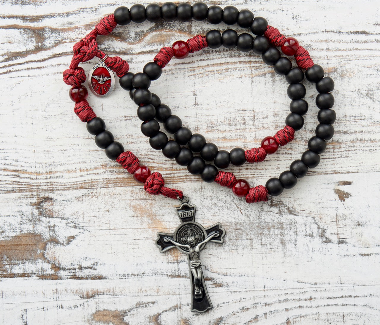 The Crimson Shield - Holy Spirit Confirmation 5 Decade Paracord Rosary in deep maroon red with dark maroon Our Father beads, matte black Hail Mary beads, and a protective black enamel 3" St. Benedict crucifix. Durable 550 paracord rosary for boys or men preparing for Confirmation Sacrament.