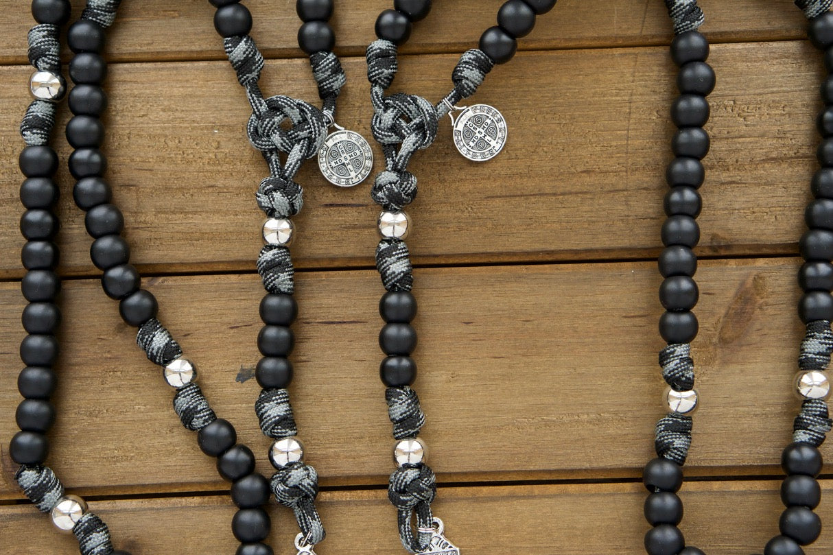 Zoomed in photo showing several Demon Destroyer black, grey and silver paracord rosaries next to each other.