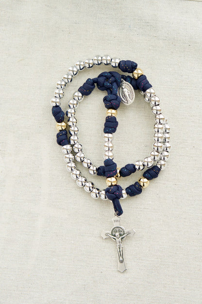 Dark blue paracord rosary with silver Hail Mary beads, gold Our Father beads, St. Benedict Crucifix, and Miraculous Medal - perfect for prayer and spiritual strength. Handmade by a small Catholic family of 6.