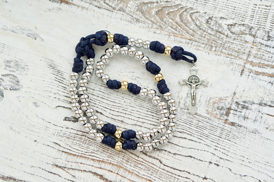 Dark blue paracord rosary with silver Hail Mary beads and gold Our Father beads, adorned with a St. Benedict Crucifix and Miraculous Medal, perfect for spiritual strength and prayer. 
