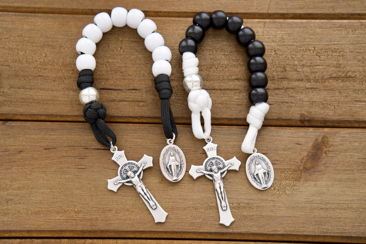 Celebrate eternal love with this Rosary Pair: Bride & Groom 1 Decade Rosary. This set of two single decade rosaries make the perfect, handmade wedding or anniversary gift for Catholic couples, featuring a white and black design with St. Benedict Crucifix and Miraculous Medal.