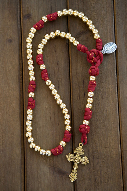 Scarlet Crown - Royal Red and Gold 5 Decade Paracord Rosary with gold Hail Mary and Our Father beads, subtle gold ribbon woven into the red paracord, premium 10mm bead size, 2" gold Pardon Crucifix and Miraculous Medal.
