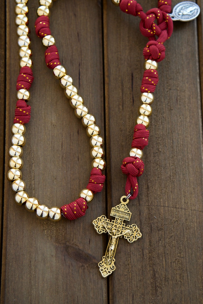 Scarlet Crown - Royal Red and Gold - 5 Decade Paracord Rosary: Handcrafted with gold beads and a striking red paracord featuring a subtle gold ribbon, this durable and unbreakable rosary is perfect for spiritual protection and devotion. Finished with a 2" gold Pardon Crucifix and Miraculous Medal.