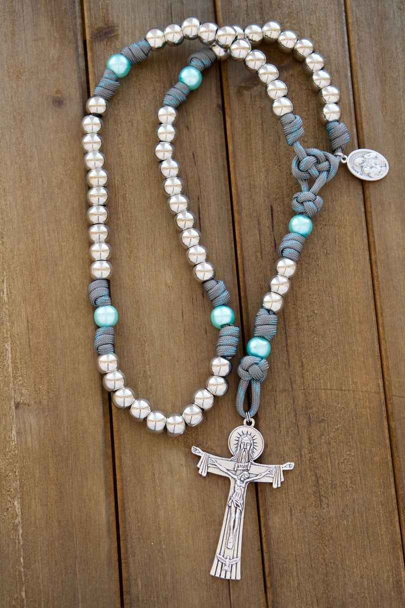St. Anne's Intercession - Sky Blue, Gray and Silver - 5 Decade Paracord Rosary: Durable, premium paracord rosary in honor of St. Anne with silver Hail Mary beads, sky blue Our Father beads, and a devotional medal. Handmade by our small Catholic family, featuring a large Holy Trinity Crucifix.