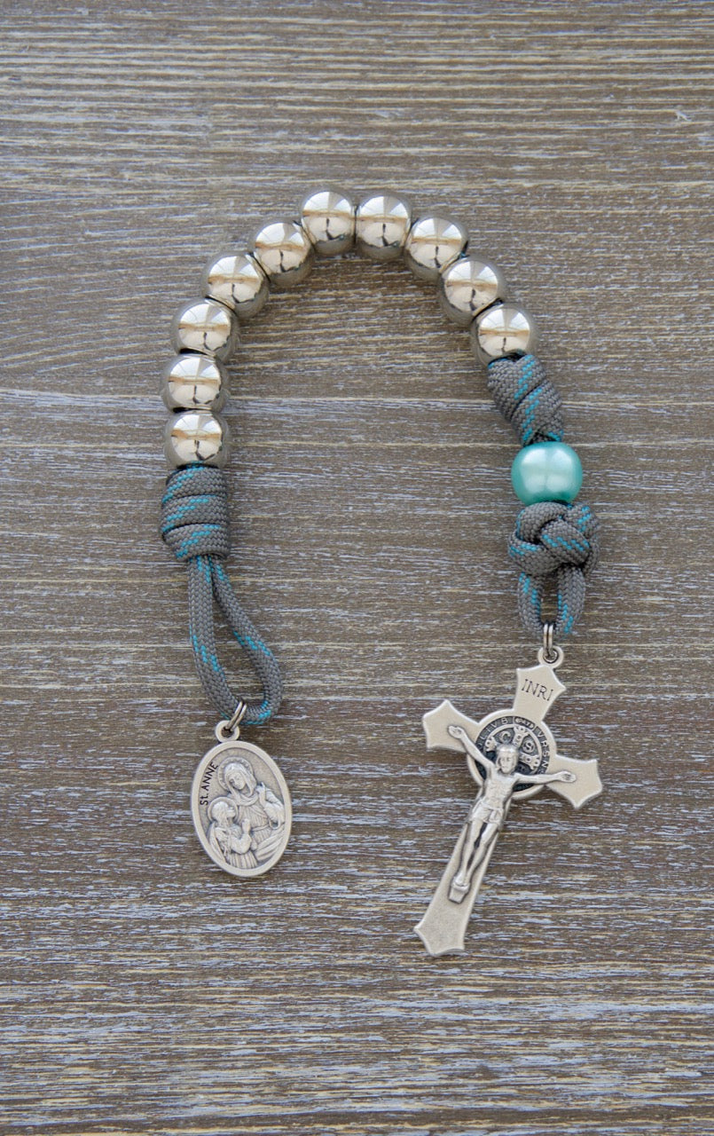 St. Anne's Intercession - 1 Decade Paracord Rosary in Gray and Blue featuring silver Hail Mary beads, sky blue Our Father beads, and a devotional St. Anne medal. Handmade by a small Catholic family for spiritual warfare and tribute to the beloved saint.