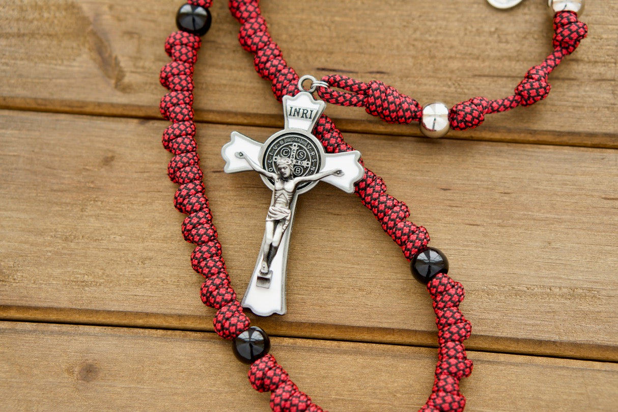 The Militia Immaculatae - St. Maximilian Kolbe Rosary features a striking red, white, and black color scheme, honoring the double crown of its patron saint. This rosary is adorned with a devotional medal showcasing the Miraculous Medal and a Saint Kolbe medal. Crafted from durable Paracord 550 rope and accented with acrylic beads, this 19-inch full size rope rosary is perfect for prayer on-the-go or in the comfort of your own home.