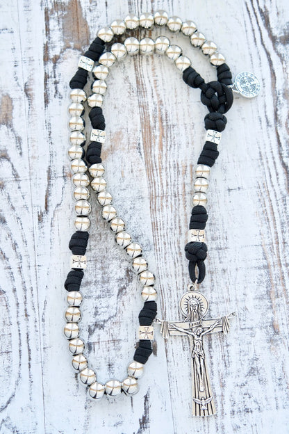 The Iron Will - Black & Silver 5 Decade Paracord Rosary: A durable, premium spiritual weapon featuring silver Hail Mary beads, unique Crusader cross Our Father beads, and a devotional St. Benedict medal centerpiece. Perfect for young Catholics to face everyday life's battles. Measures 19 inches with a full-size Holy Trinity Crucifix.